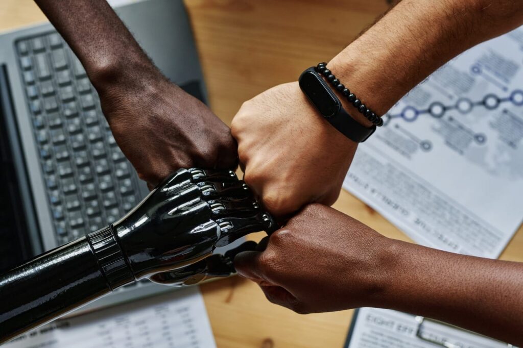 four hands fist bumping , one is robotic